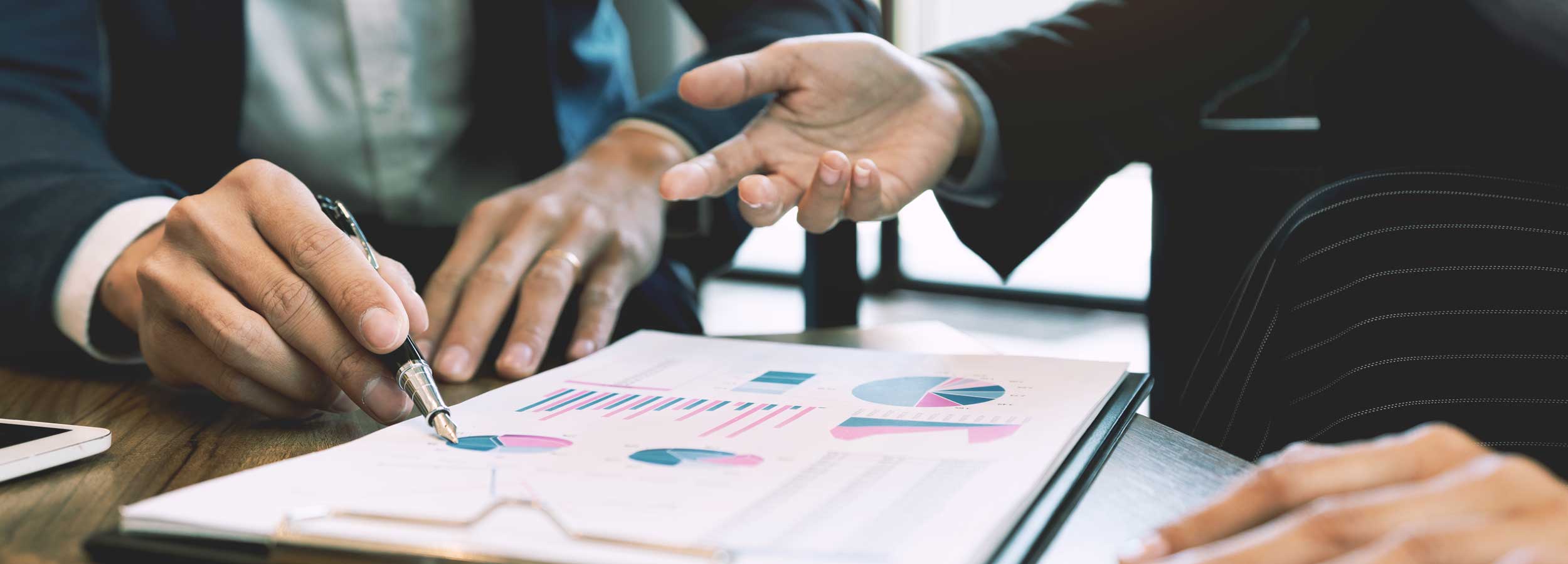 People sitting around a table looking over graphs in a business setting.