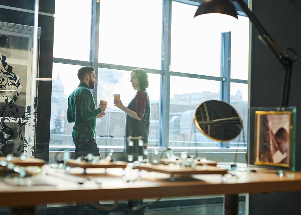 Image of two people talking near the window of a retail store.