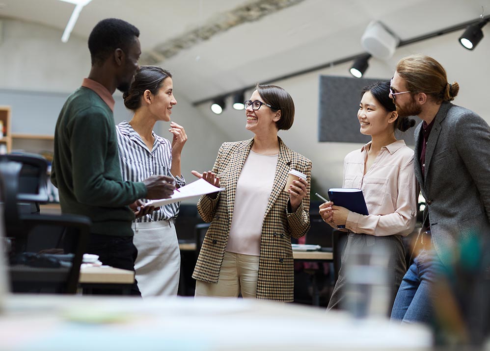 Image of five office workers, talking and laughing